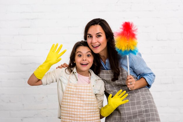 Mãe e filha posando com objetos de limpeza