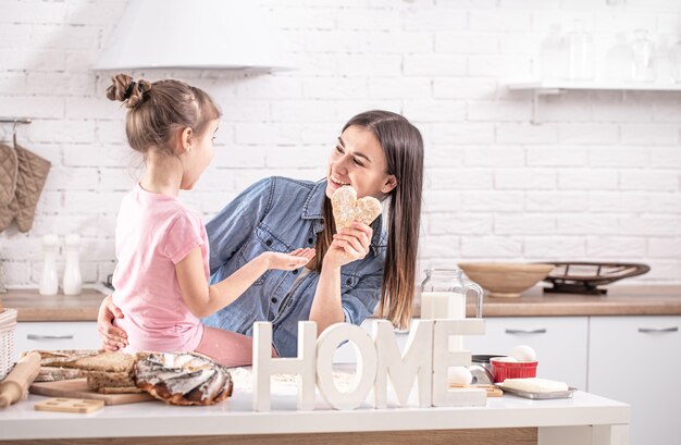 Mãe e filha preparam bolos na cozinha.