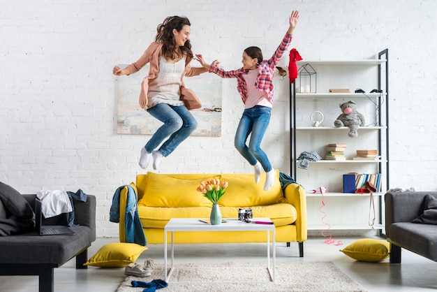 Mãe e filha pulando na sala de estar