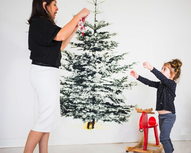 Mãe e filha que decoram a árvore de natal