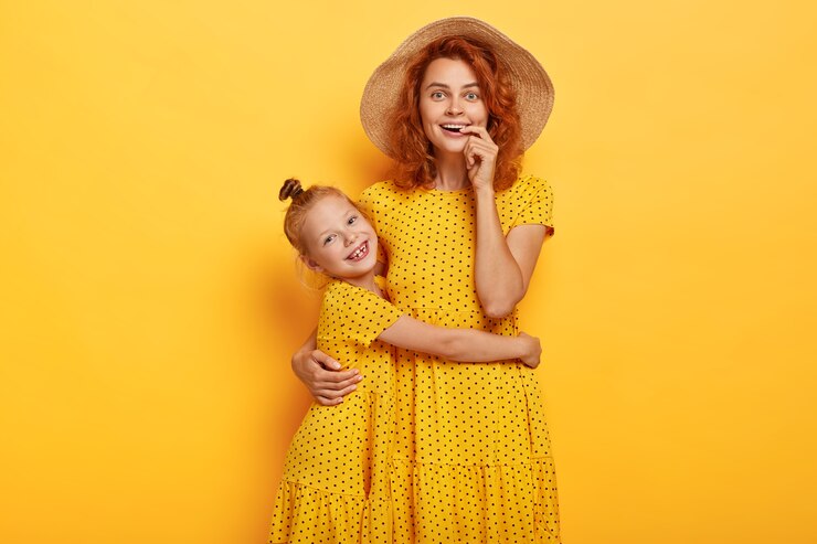 Foto grátis mãe e filha ruivas felizes posando em vestidos semelhantes