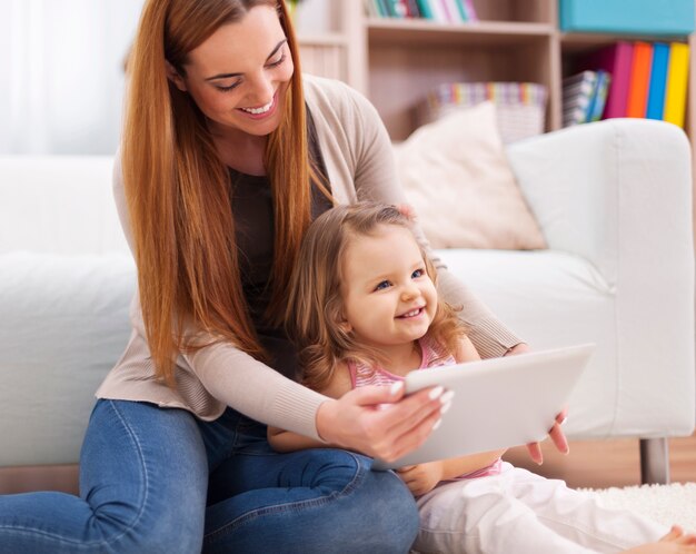 Mãe e filha se divertem durante o uso do tablet digital