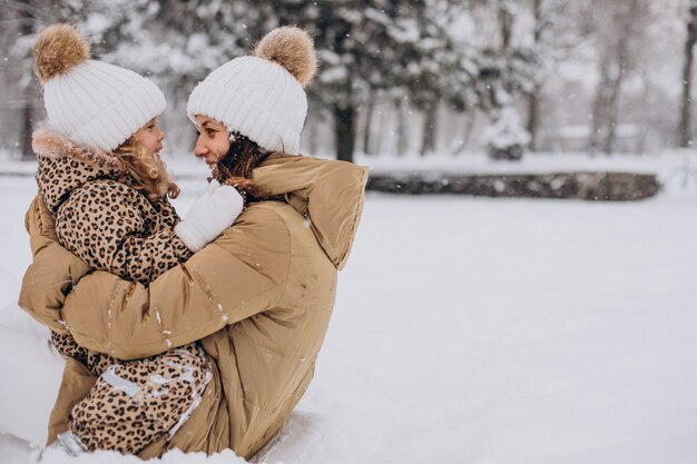 Mãe e filha se divertindo em um parque cheio de neve