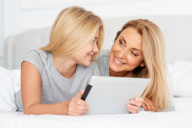 Mãe e filha segurando o tablet e olhando um ao outro