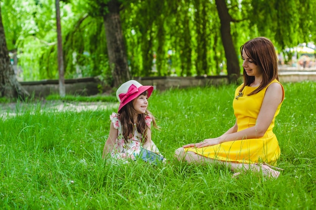 Mãe e filha sentada no gramado de um parque