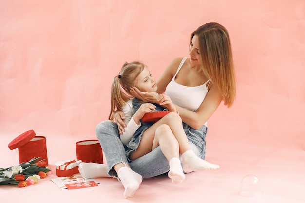 Mãe e filha sentadas juntas. parede rosa. conceito do dia das mães.