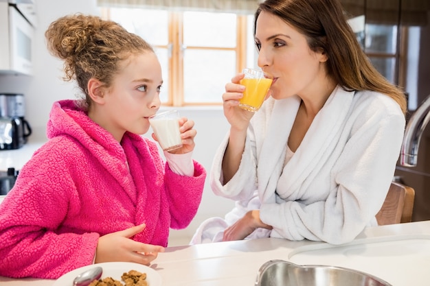 Mãe e filha ter café da manhã na cozinha