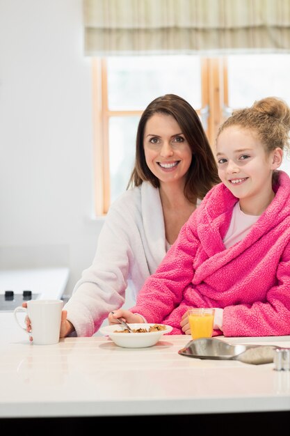 Mãe e filha ter café da manhã na cozinha