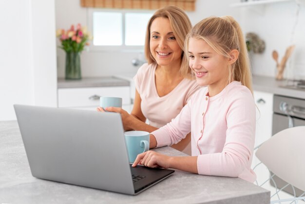 Mãe e filha trabalhando no laptop