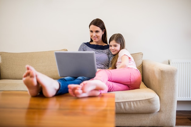 Mãe e filha, usando laptop na sala de estar