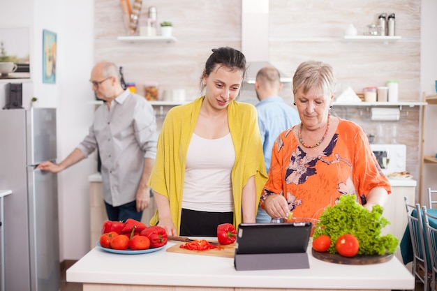 Mãe e filha verificando a receita de salada de legumes no tablet pc na cozinha.