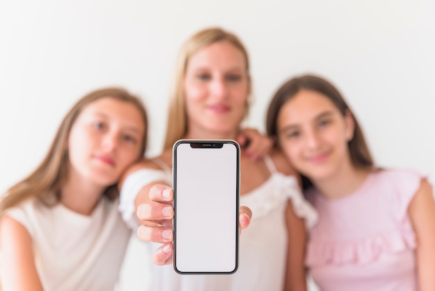 Foto grátis mãe e filhas segurando smartphone com tela em branco