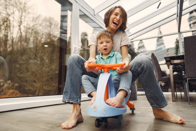 Mãe e filho andam pelo apartamento em um carro de brinquedo