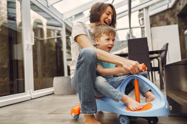 Mãe e filho andam pelo apartamento em um carro de brinquedo