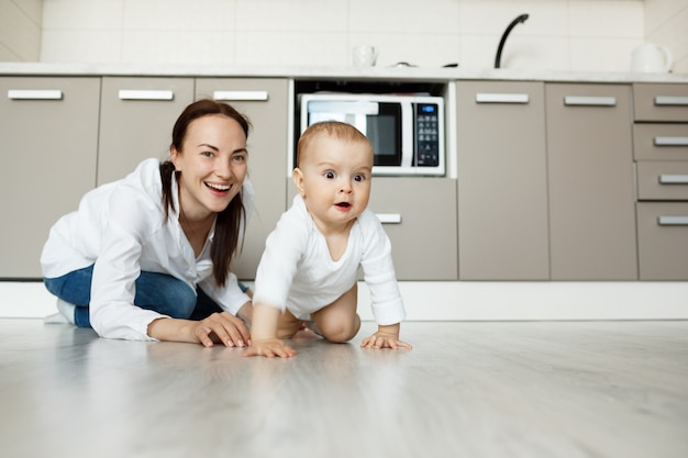 Mãe e filho brincando no chão da cozinha, se divertindo