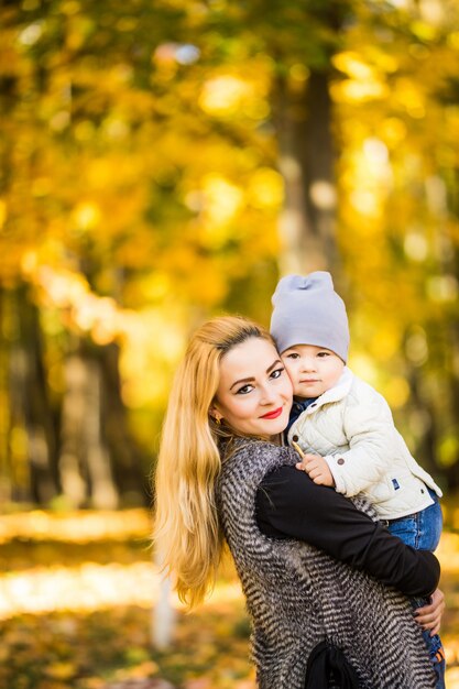 Mãe e filho caminhando no parque outono dourado
