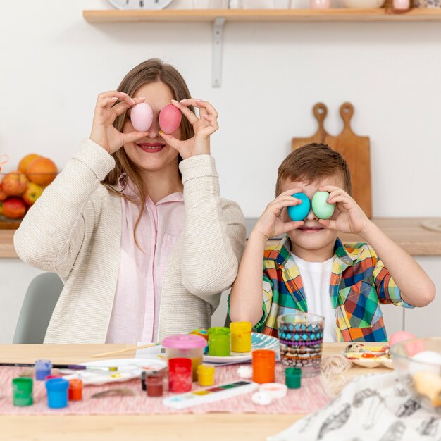 Mãe e filho, cobrindo os olhos com ovos pintados