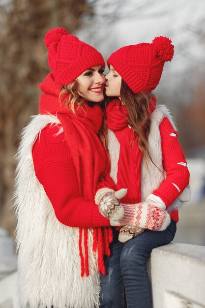 Mãe e filho com chapéus de malha de inverno nas férias de Natal em família. Chapéu de lã feito à mão e lenço para mãe e filho. Tricô para crianças. Casacos de malha. Mulher e menina em um parque.