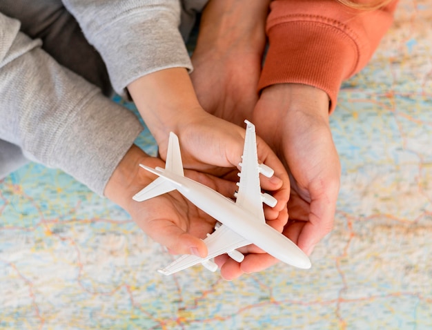 Mãe e filho em casa segurando uma estatueta de avião no topo do mapa