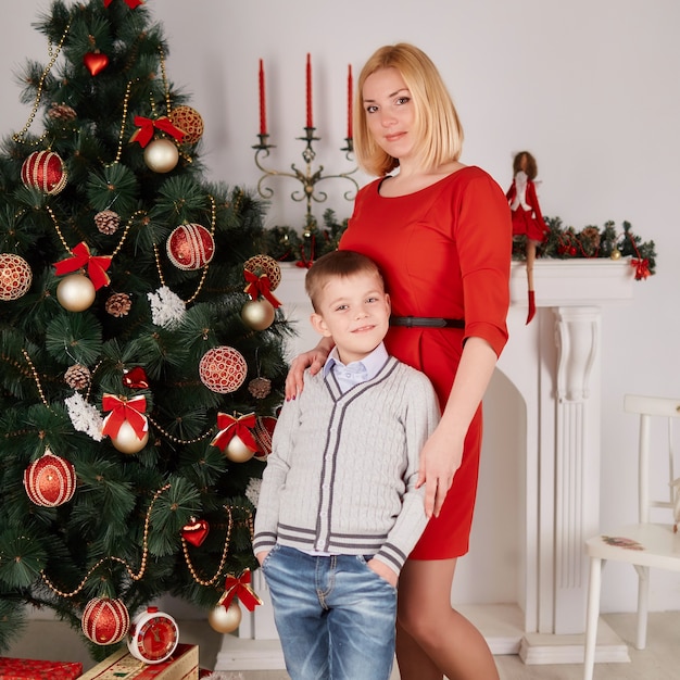 Mãe e filho em pé ao lado da árvore de natal