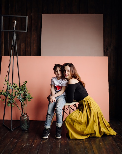 Mãe e filho estão posando no estúdio e vestindo roupas casuais