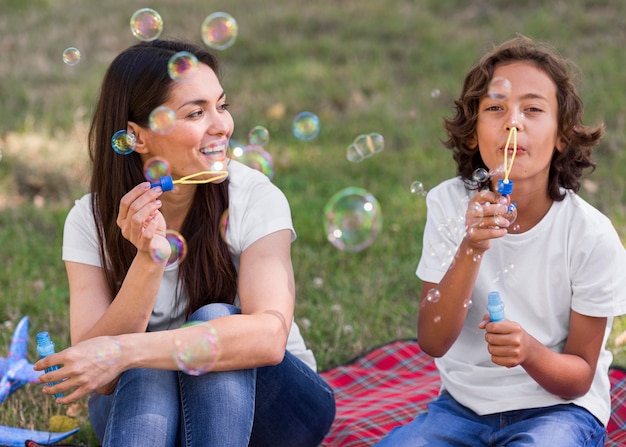 Mãe e filho fazendo balões ao ar livre juntas