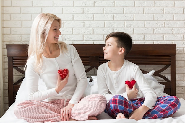 Mãe e filho na cama com pequenos corações