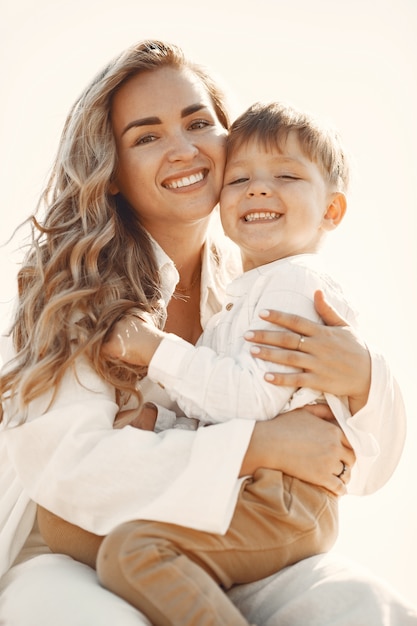 Mãe e filho. Pilha de feno ou fardo no campo de trigo amarelo no verão. Crianças se divertindo juntos.