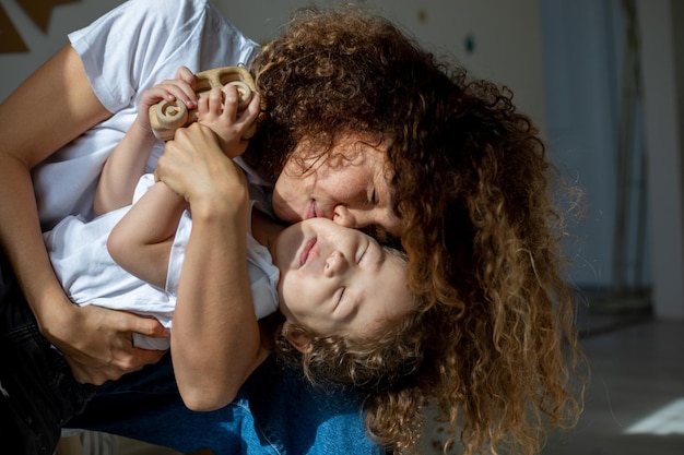 Foto grátis mãe e filho rizados brincam contra o fundo da inscrição feliz aniversário