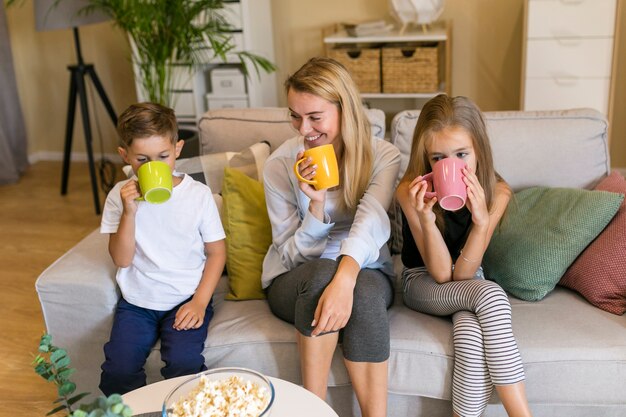 Mãe e filhos bebendo de xícaras vista frontal