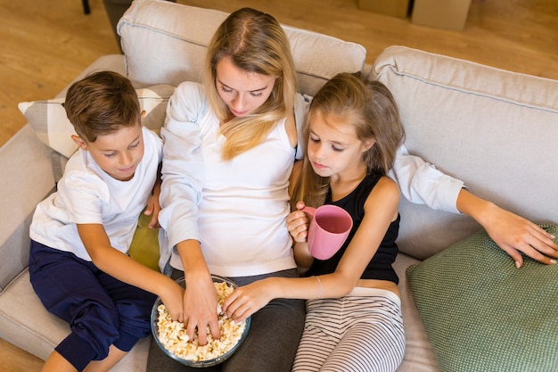 Mãe e filhos comendo pipoca da tigela de venda