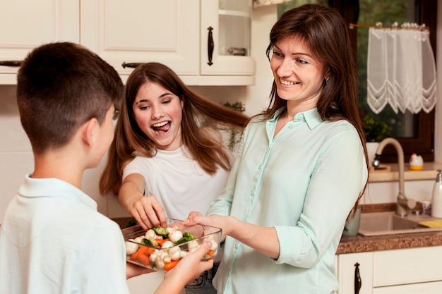 Mãe e filhos na cozinha juntos a preparar comida