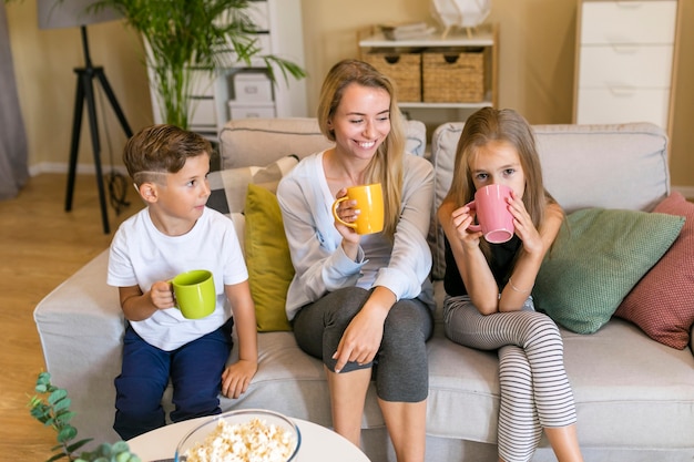 Mãe e filhos sentados em um sofá vista frontal