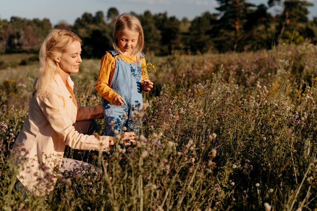 Mãe e menina em tiro médio na natureza