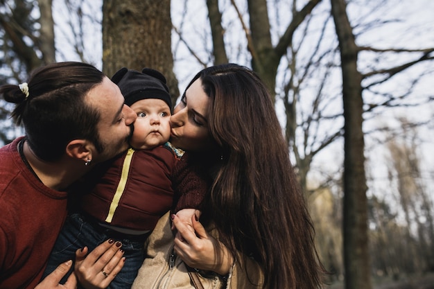 Foto grátis mãe e pai beijando bebê