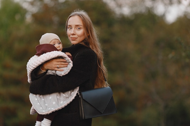 Mãe elegante com filha. pessoas caminham lá fora. mulher com uma jaqueta preta.