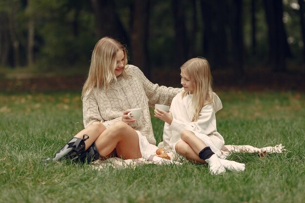 Mãe elegante com filha. Pessoas sentadas na grama