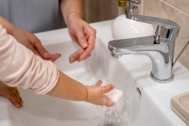 Mãe ensinando criança a lavar as mãos