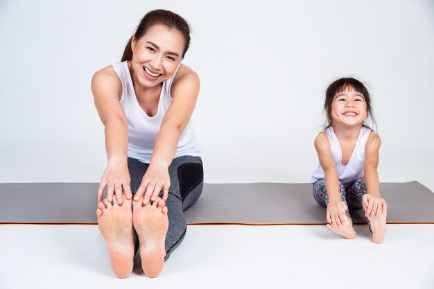 Mãe ensinando filha a alongar os músculos da perna.