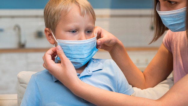 Mãe ensinando filho a usar máscara facial