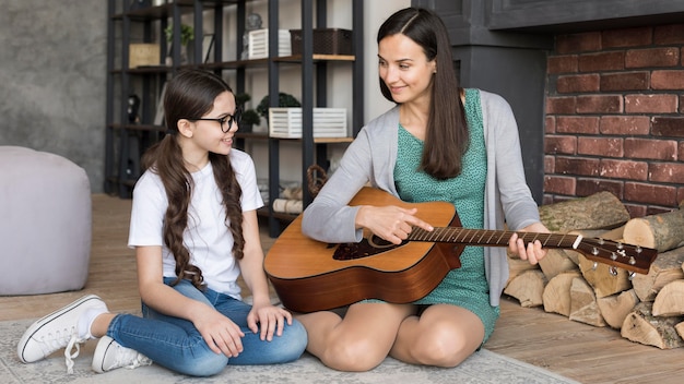 Mãe ensinando menina a tocar violão