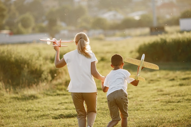 Mãe europeia e filho africano. Família em um parque de verão. As pessoas brincam com o avião.