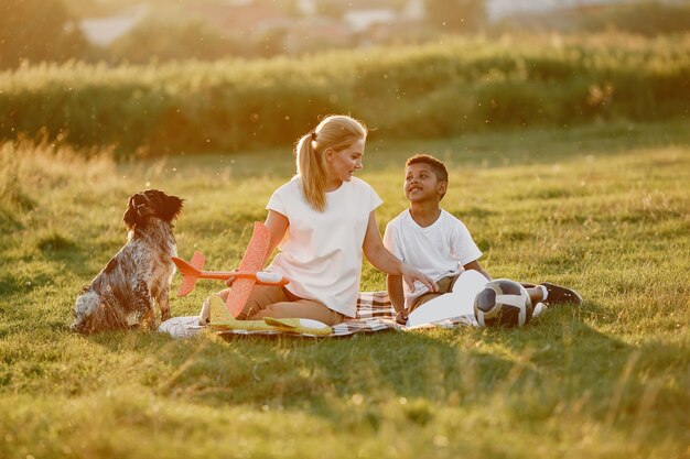 Mãe europeia e filho africano. Família em um parque de verão. Pessoas sentadas no cobertor.