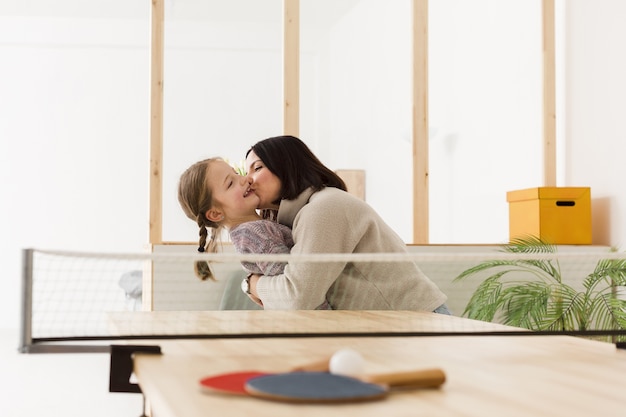 Foto grátis mãe feliz, beijando a filha dentro de casa