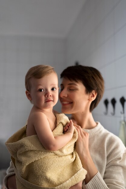 Mãe feliz segurando o bebê em tiro médio