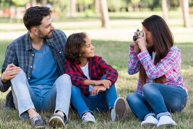 Mãe fotografando pai e filho ao ar livre no parque