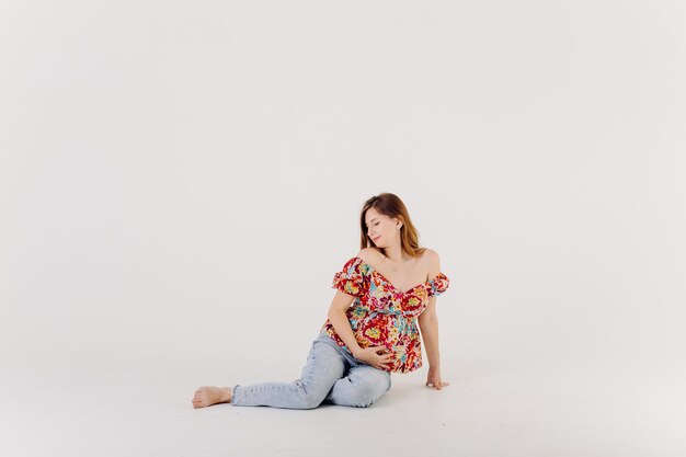 Mãe grávida elegante em vestido posando de orgulho de sua gravidez