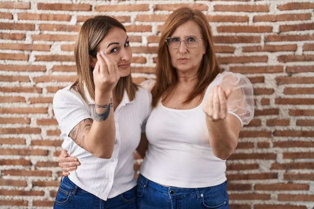 Foto grátis mãe hispânica e filha vestindo camiseta branca casual fazendo gesto italiano com mão e dedos expressão confiante