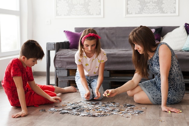 Mãe jogando quebra-cabeça com seus filhos em casa