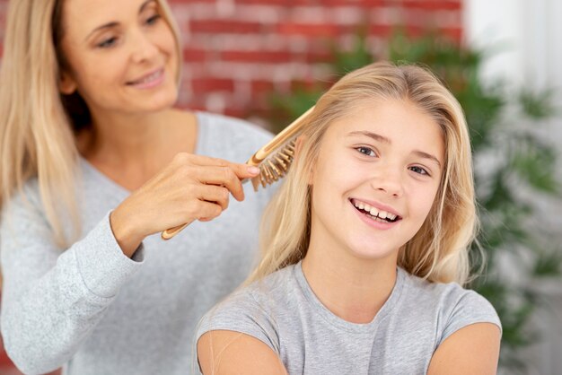 Mãe loira, penteando o cabelo da filha